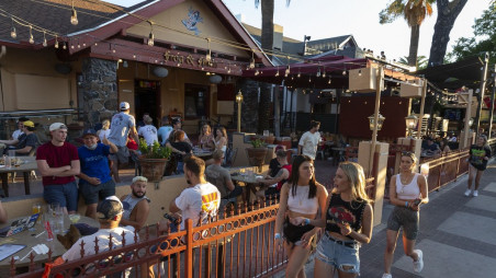 Pedestrians walk past customers sitting outside at a bar in Tucson, Arizona on May 11, 2020. 
Photographer: Cheney Orr/Bloomberg
