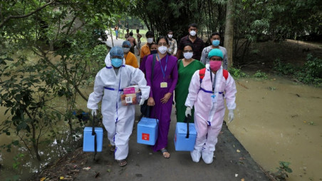 Healthcare workers carry COVISHIELD vaccine, a coronavirus disease (Covid-19) vaccine manufactured by Serum Institute of India, to inoculate villagers during a door-to-door vaccination and testing drive at Uttar Batora Island in Howrah district in West Bengal state, India, June 21, 2021. REUTERS