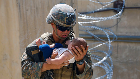A US Marine comforts an infant while they wait for the mother during an evacuation at Hamid Karzai International Airport, Afghanistan, August 21, 2021. Picture taken August 21, 2021. Photo :Reuters