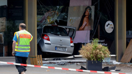 A man wearing a police vest walks near a car that crashed into a group of people and ended up in a storefront near Breitscheidplatz in Berlin, Germany on 8 June 2022. Photo: Reuters