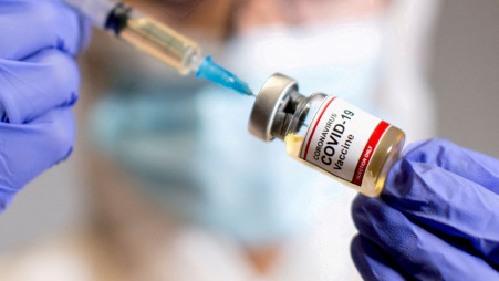 Une femme tient une petite bouteille étiquetée avec un "vaccin contre le coronavirus COVID-19"  autocollant et une seringue médicale dans cette illustration prise le 30 octobre 2020. REUTERS/Dado Ruvic/File Photo