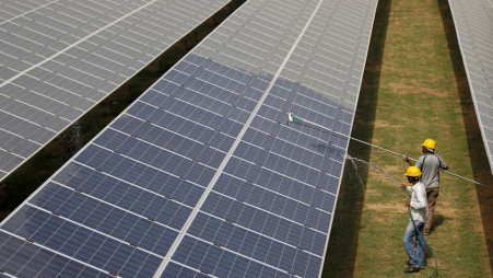 Workers clean photovoltaic panels inside a solar power plant in Gujarat, India, July 2, 2015. REUTERS/Amit Dave