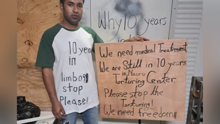 Mohammad Kaium stands with his lips sewn together, holding a placard that calls for medical treatment and freedom from 10 years of immigration detention on Nauru Island. Photo: Mohammad Shofiqul Islam
