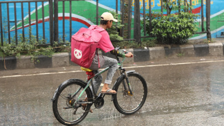Pengendara pengantaran makanan mengayuh sepedanya melewati jalan basah di Dhaka, memastikan pengiriman tepat waktu meskipun hujan deras. Foto: Syed Zakir Hossain/TBS