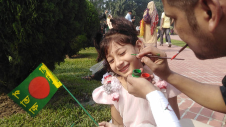 Five year old Sondhya smiles as someone draws a flag in her cheeck on the National Martyrs' Memorial grounds in Savar, Dhaka on 16 December 2023. Photo: Noman Mahmud