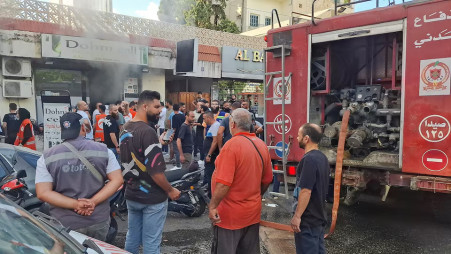 People gather as smoke rises from a mobile shop in Sidon, Lebanon September 18, 2024. REUTERS/Hassan Hankir
