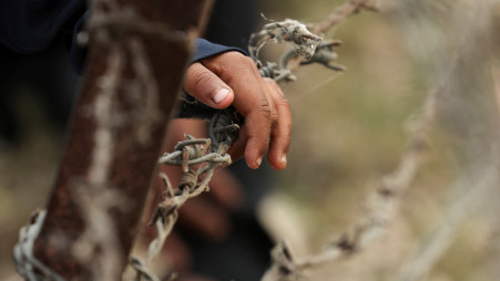 A child from Pakistan places his hand on barbed wire as he waits to go to Pakistan at the Attari-Wagah border crossing, after India revoked visas and suspended visa services to Pakistani citizens. Photo: Reuters
