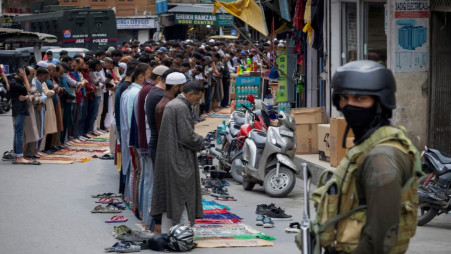 Kashmiri muslims offer Friday prayers on a road as a security personnel stands guard, in Srinagar, May 2, 2025. REUTERS/Adnan Abidi