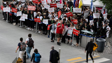 Passengers look at demonstrators holding placards as Air Canada flight attendants said they will remain on strike and challenge a return-to-work order they called unconstitutional, defying a government decision to force them back to their duties, at Vancouver International Airport in Richmond, British Columbia, Canada, August 17, 2025. Photo: REUTERS/Chris Helgren