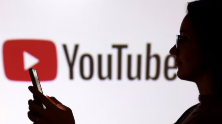 A teenager poses for a photo while holding a smartphone in front of a Youtube logo in this illustration taken September 11, 2025. REUTERS/Dado Ruvic/Illustration 