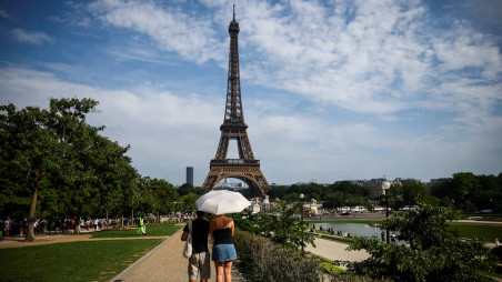 People protect themselves from the sun under an umbrella near the Eiffel Tower as temperatures rise in Paris during a second heatwave affecting a large part of France, June 20, 2026. REUTERS/Sarah Meyssonnier
