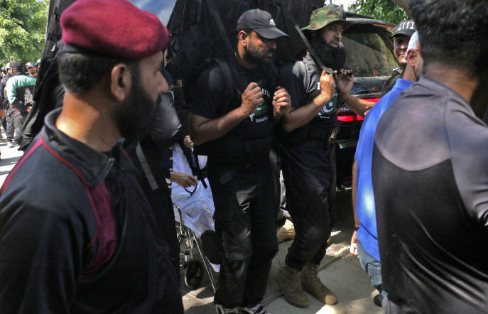 Pakistan&#039;s former Prime Minister Imran Khan sits in a wheelchair as his private security guards use shields to guard him upon his arrival to appear at a court in Islamabad, Pakistan, May 9, 2023. REUTERS/Stringer
