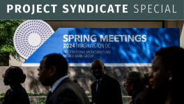 Attendees walk past signage for the IMF and World Bank spring meetings outside the IMF HQ in Washington, DC on 15 April. PHOTO: BLOOMBERG