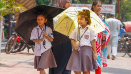 Two students of Kakoli High School and College in Dhaka&#039;s Satmasjid Road go to school holding umbrellas amid extreme heat as schools and colleges open after a week of closure due to heatwave. Photo: Syed Zakir Hossain